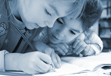 Two young children working together writing