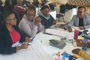 Sat around a table a group of teachers are deep in discussion and though | Aga Khan University