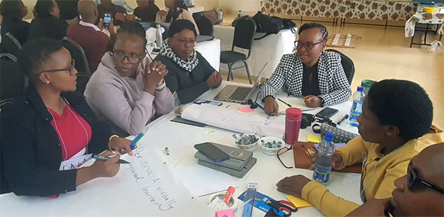  Sat at a table a group of teachers are deep in discussion and thought | Aga Khan University