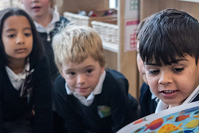 Read more about DIALLS A primary school pupil reads an open book to other children