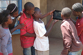 Read more about the EdTech Hub School children stand looking at something on a tablet computer